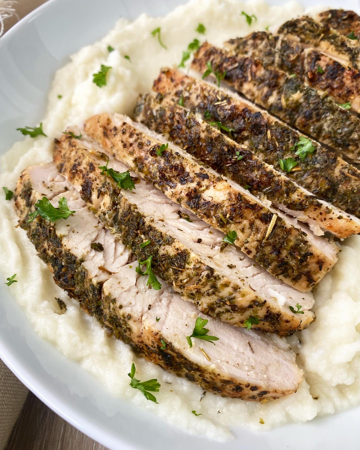 close up overhead shot of air fryer turkey breast tenderloin on mashed cauliflower served in a white bowl