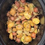 overhead shot of cooked Garlic Parmesan Potatoes in a black slow cooker