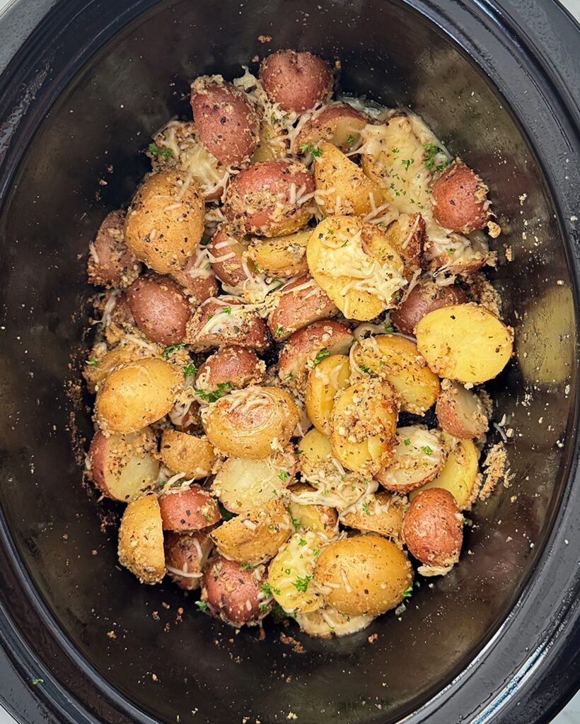 overhead shot of cooked Garlic Parmesan Potatoes in a black slow cooker