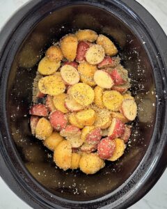 overhead shot of uncooked Garlic Parmesan Potatoes in a black slow cooker