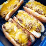 close up shot of cooked chili cheese dogs in a black air fryer