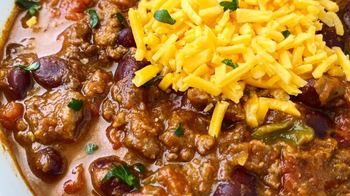 side view close up shot of pumpkin chili in a white bowl with a silver spoon