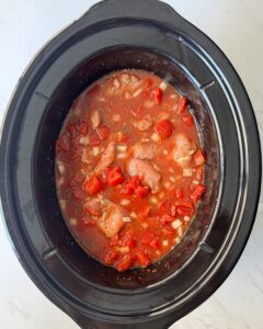 overhead shot of uncooked Chicken Okra Tomatoes in a black slow cooker