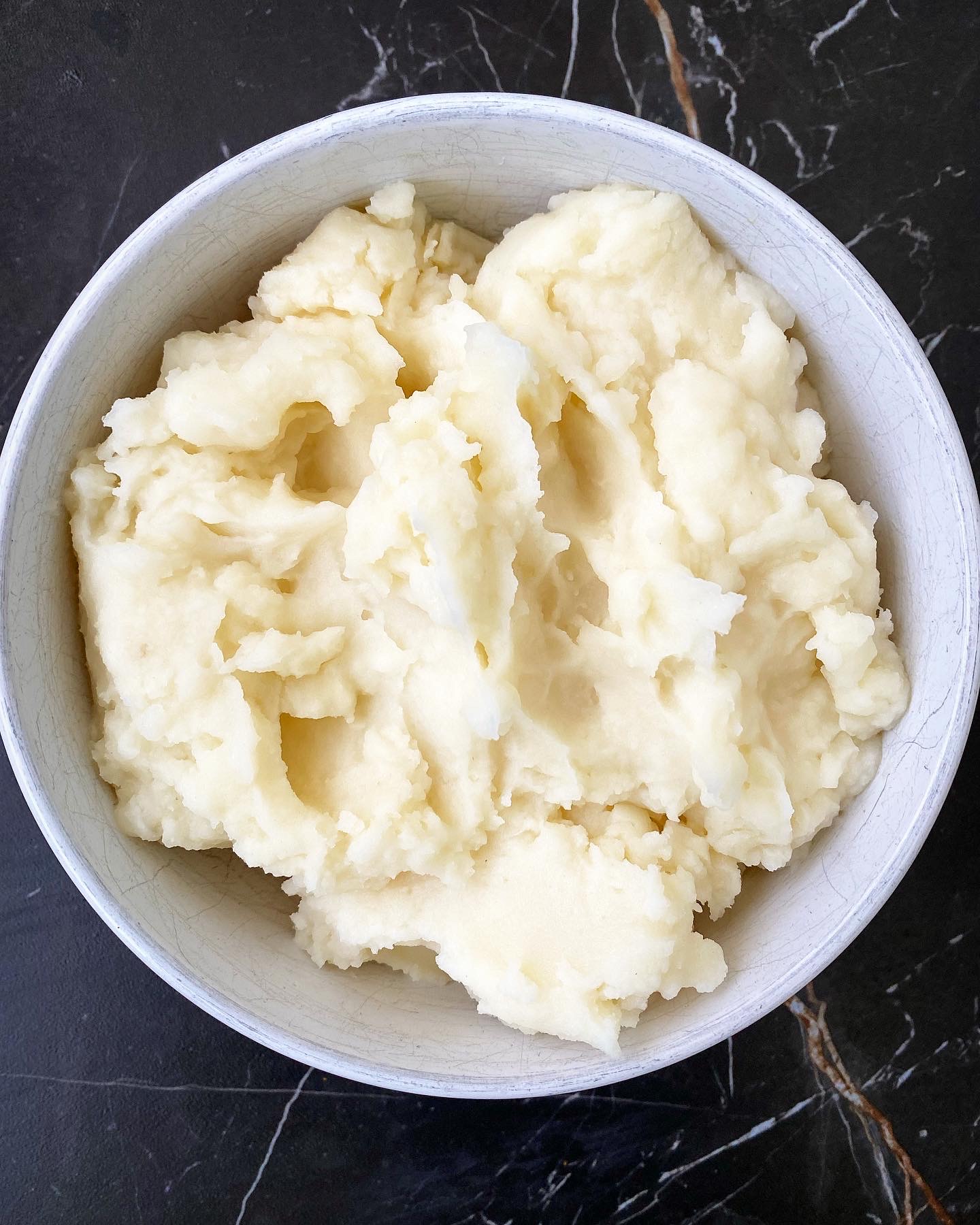 overhead shot of cooked mashed potatoes in a white bowl