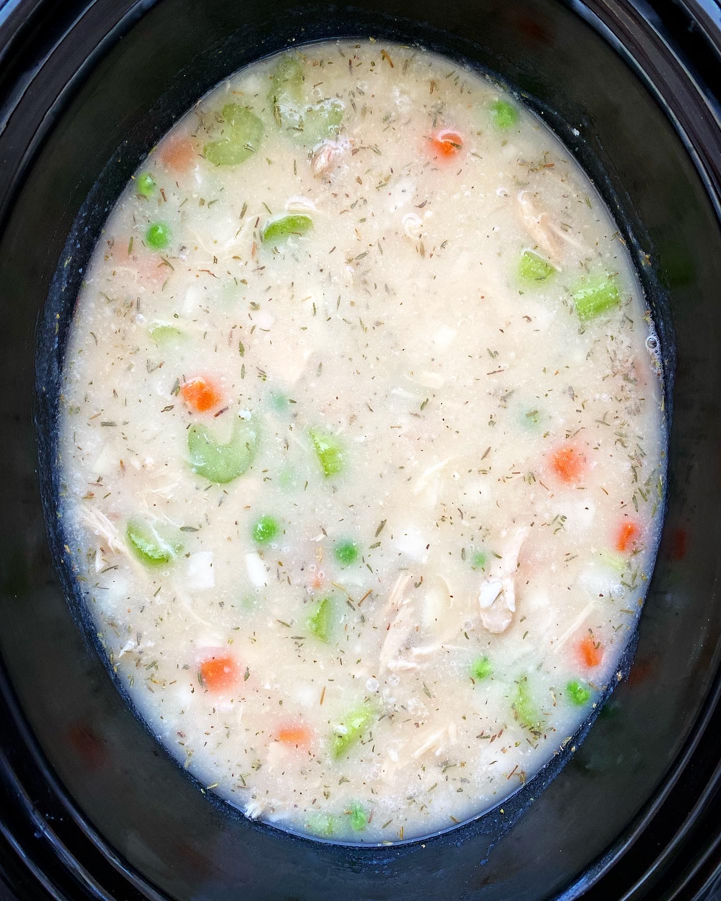 overhead shot of uncooked turkey mashed potato soup in a black slow cooker