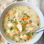overhead shot of cooked turkey mashed potato soup in a white bowl with a spoon