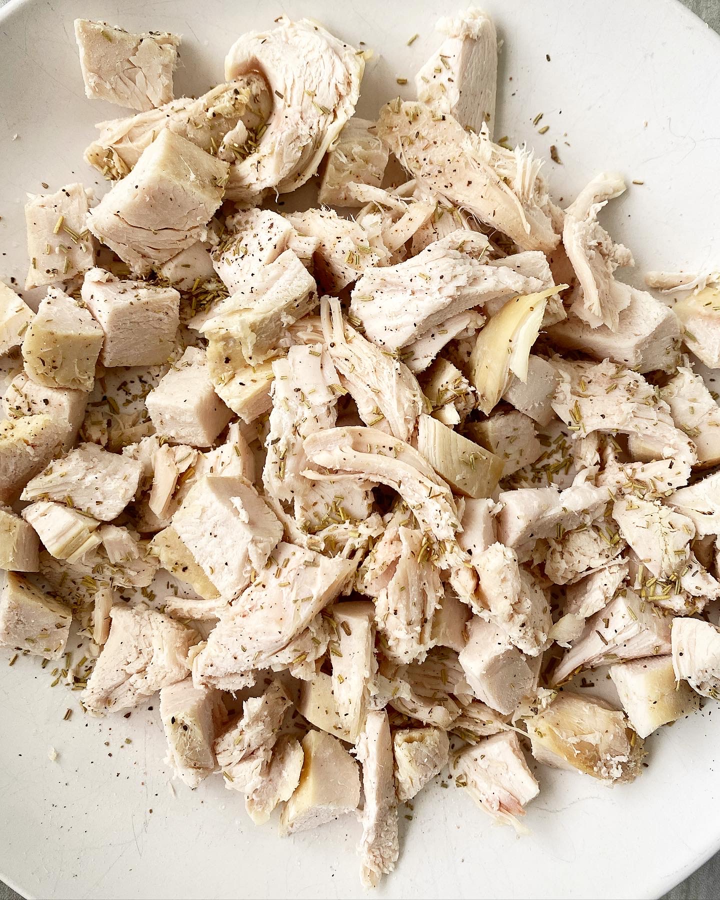 overhead shot of turkey seasoned with salt, pepper, and dried thyme on a white plate