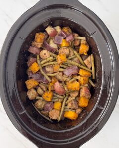 overhead shot of cooked vegetables in a black slow cooker