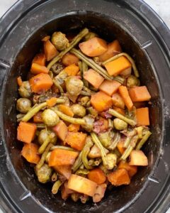 overhead shot of cooked harvest vegetables in a black slow cooker