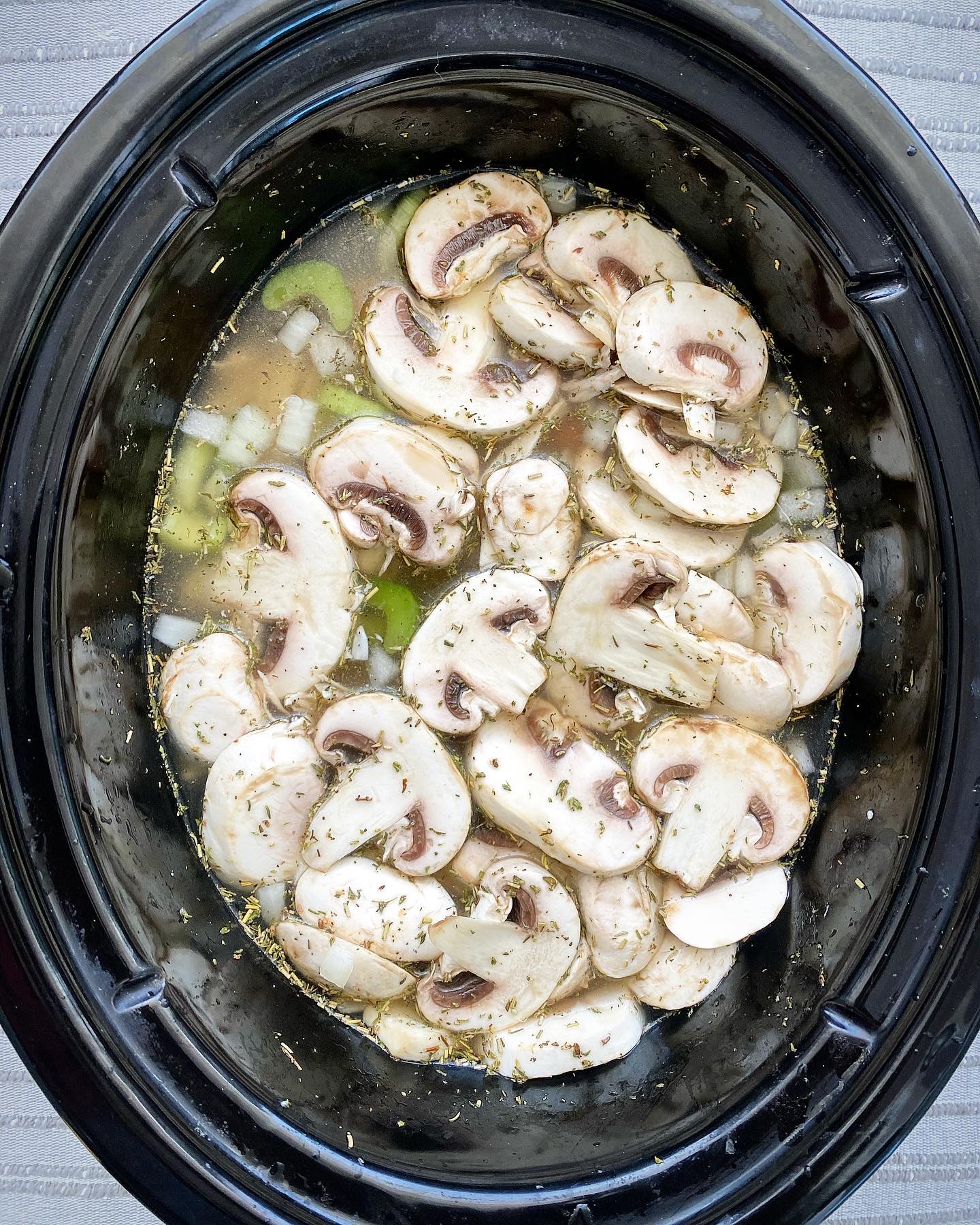 overhead shot of uncooked Crockpot Turkey Wild Rice Soup in a black slow cooker