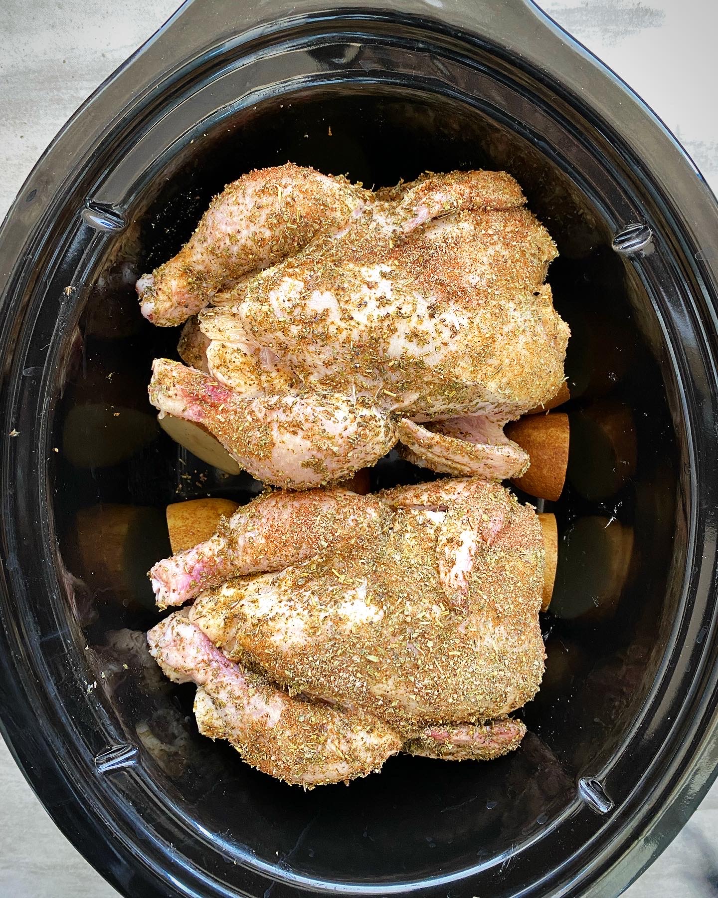 overhead shot of uncooked Cornish hens in a black slow cooker