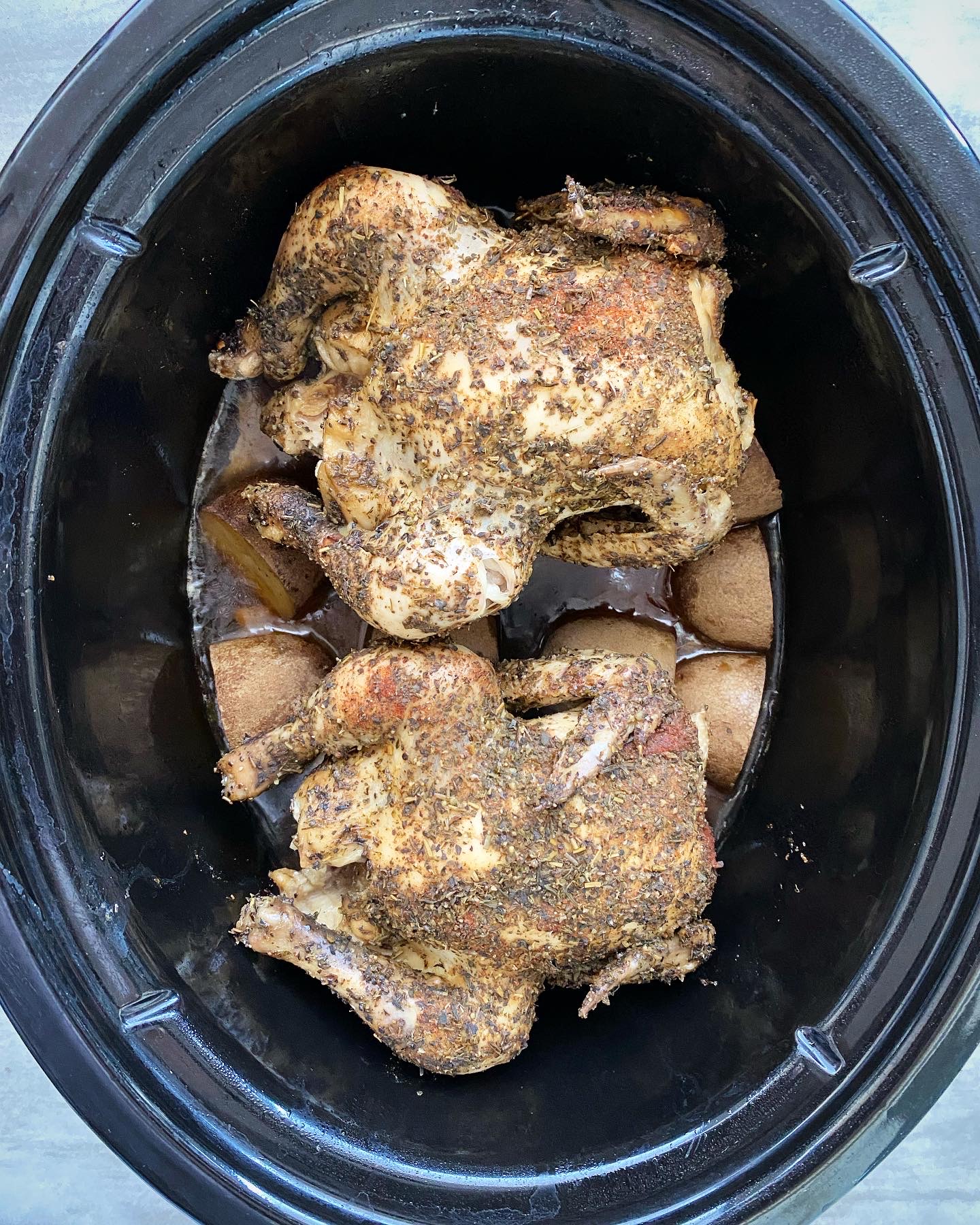 overhead shot of cooked Cornish hens in a black slow cooker