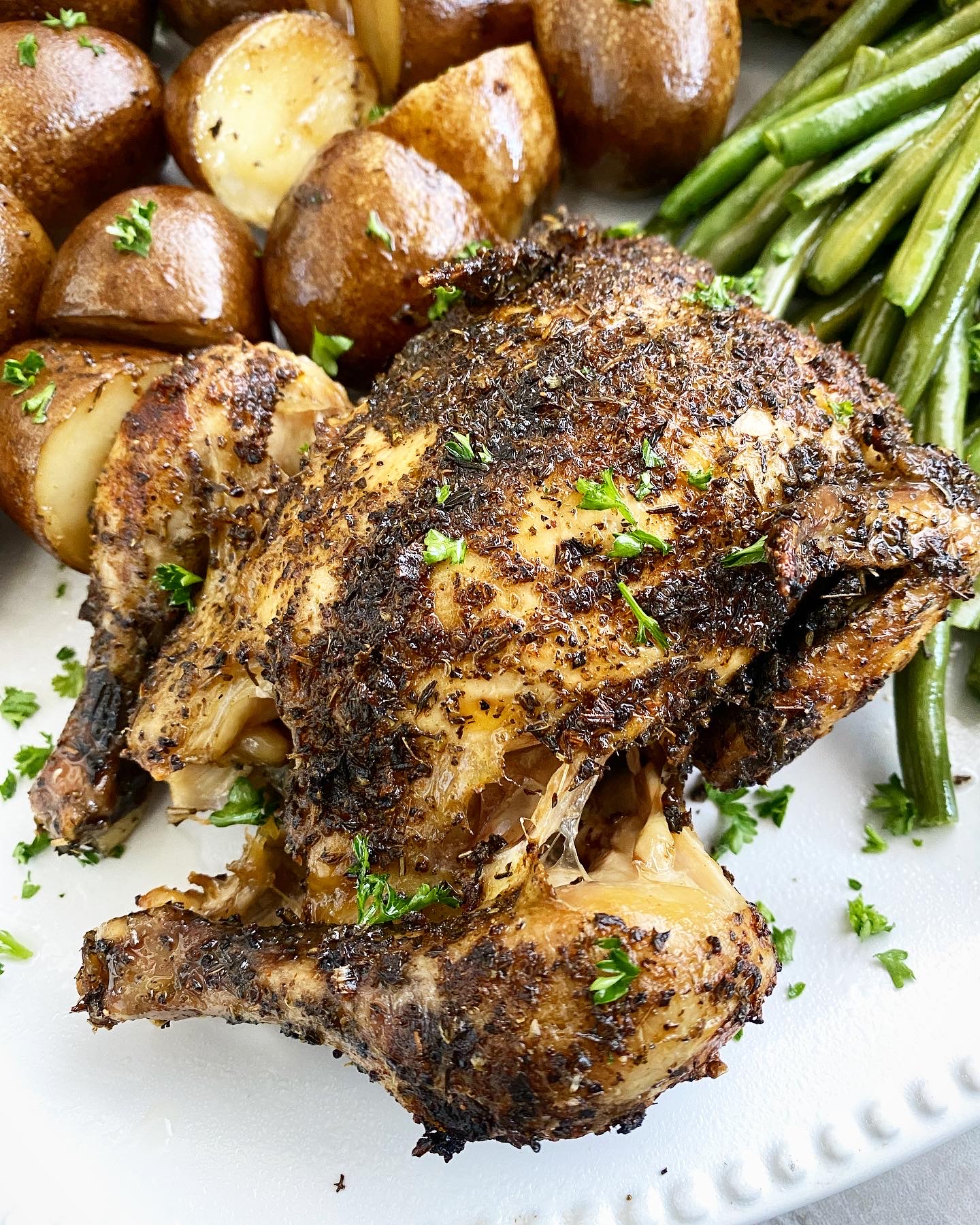 close up shot of cooked Cornish hens, on a white platter