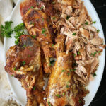 overhead shot of cooked slow cooker turkey legs on a white platter