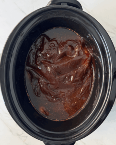 overhead shot of cooked BBQ brisket in a black slow cooker