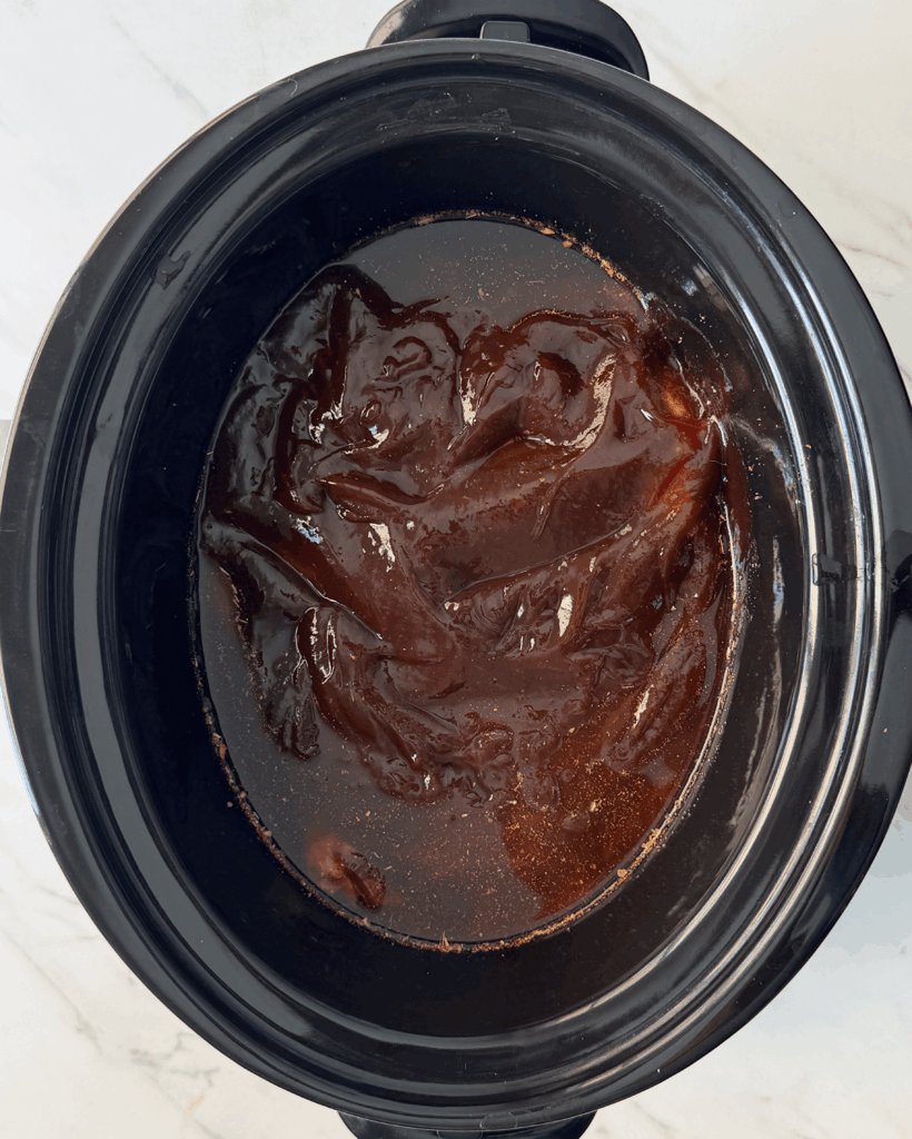overhead shot of cooked BBQ brisket in a black slow cooker