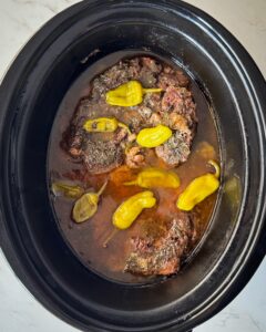 overhead shot of cooked Mississippi Beef in a black slow cooker