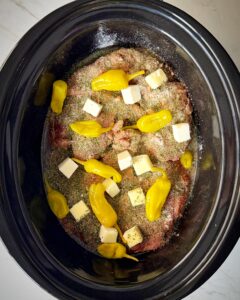 overhead shot of uncooked Mississippi Beef in a black slow cooker