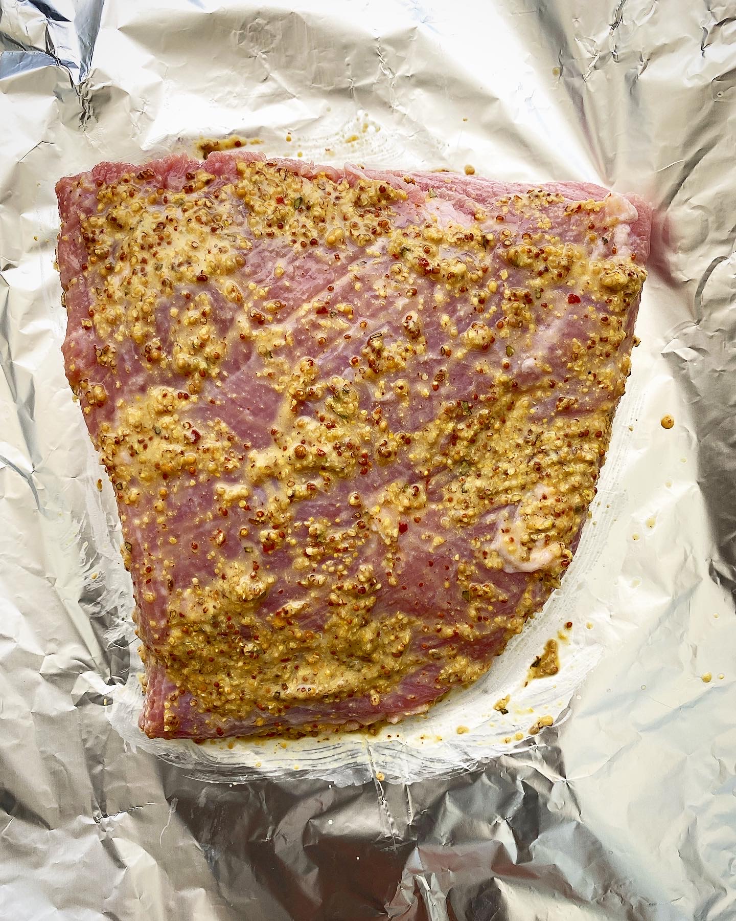 uncooked corned beef with mustard mixture on top in the air fryer