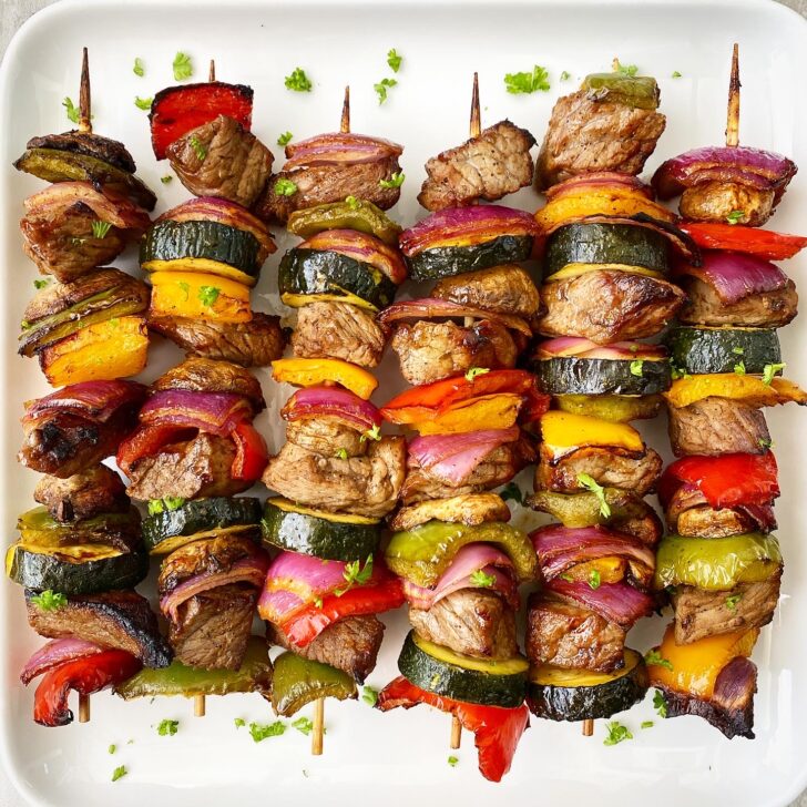 cooked Creole beef kebabs on a white plate