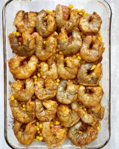 shrimp boil casserole with uncooked shrimp on top