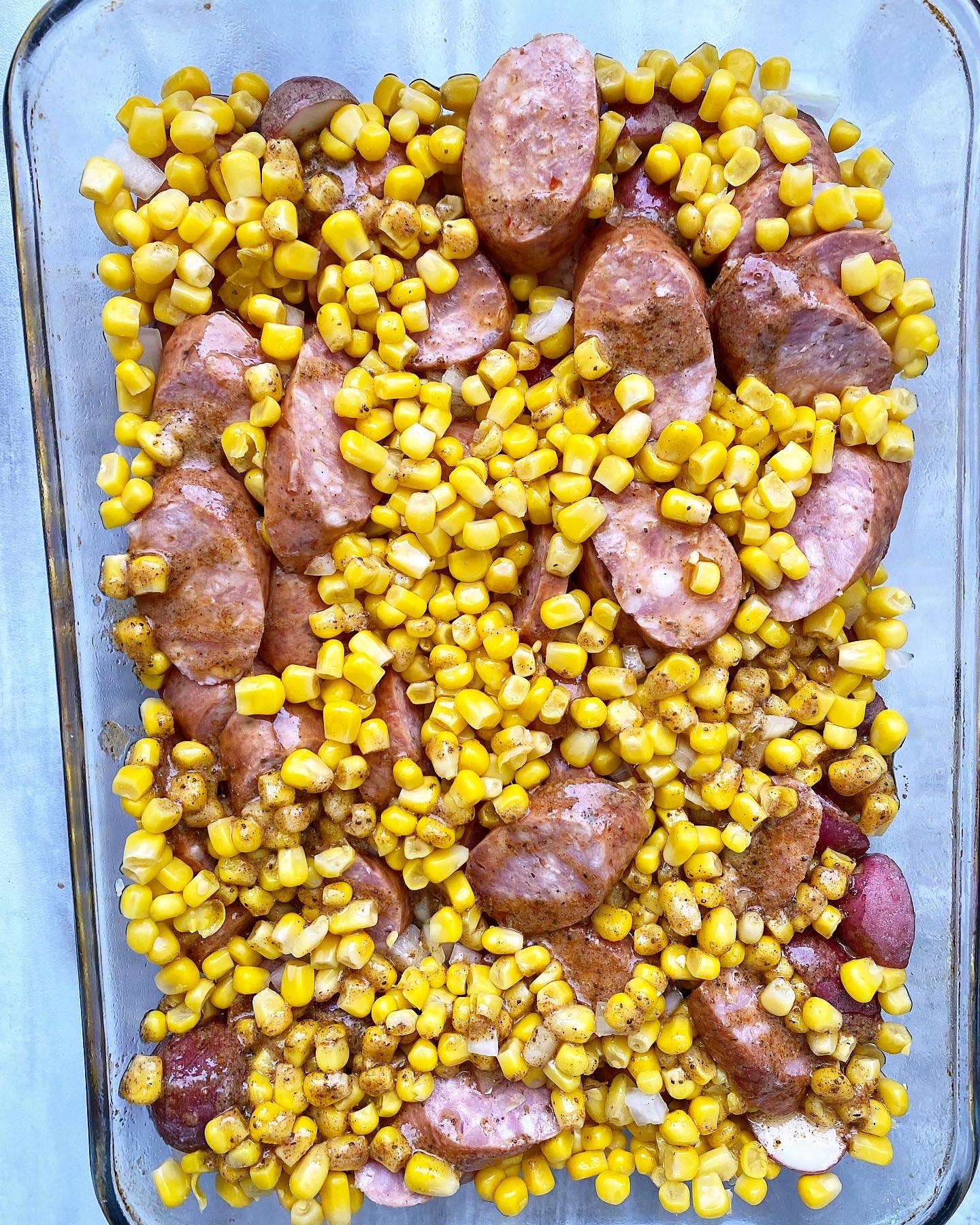 potatoes, sausage, onion, and corn in a casserole dish