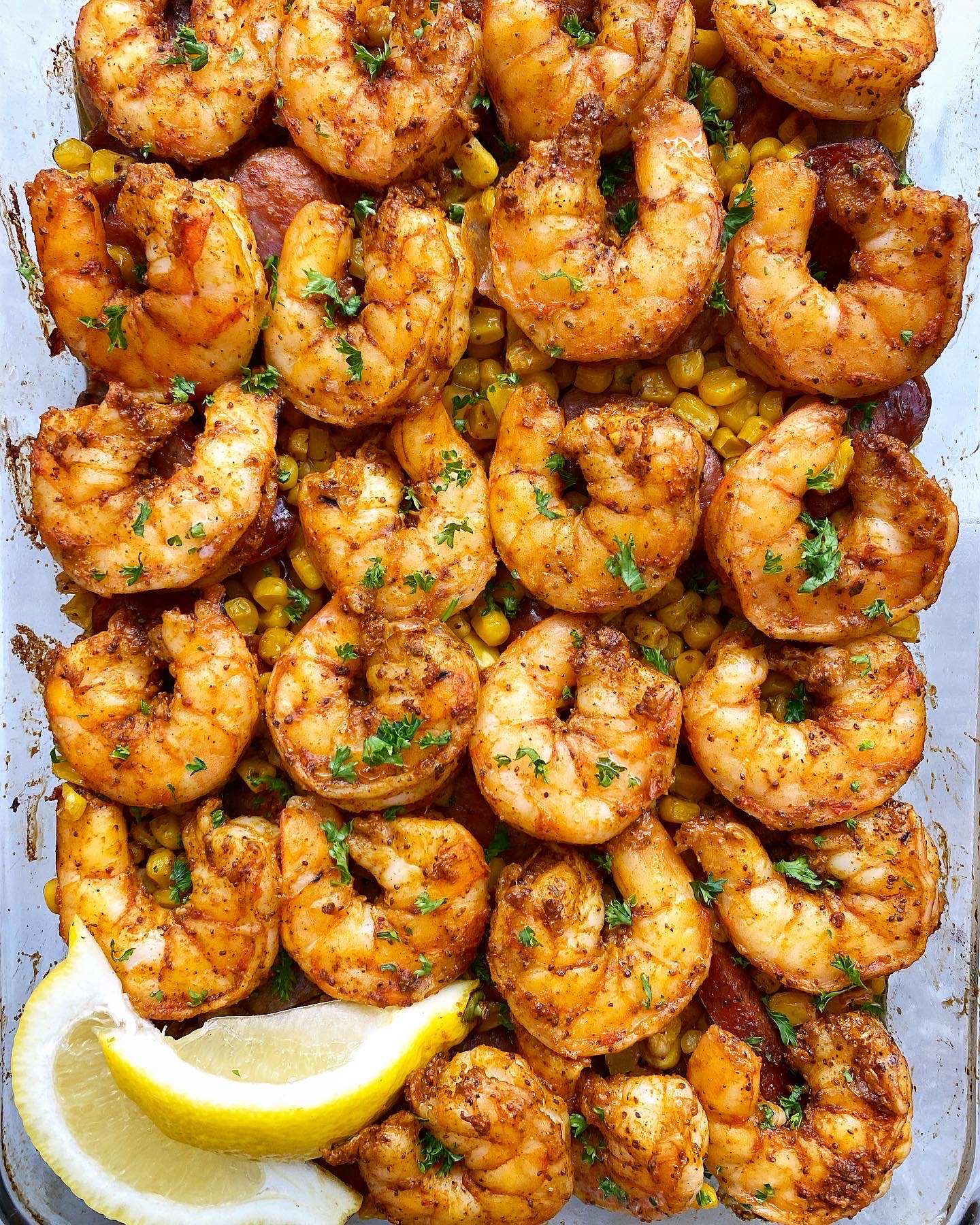 overhead close up shot of baked shrimp boil casserole in a clear baking dish