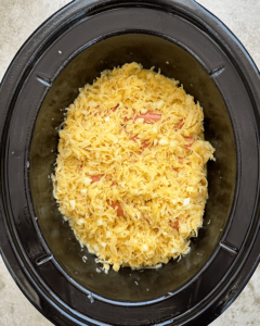 overhead shot of uncooked hot dogs covered in sauerkraut a black slow cooker