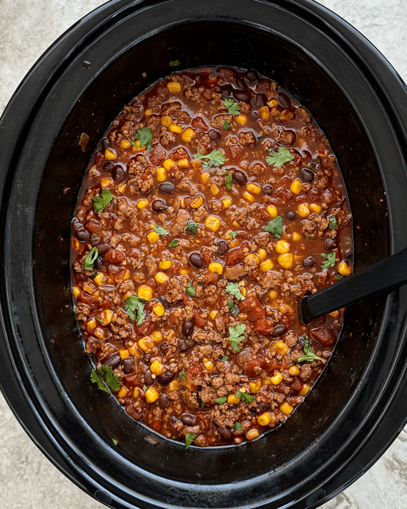 overhead shot of cooked chorizo beef chili in a black slow cooker