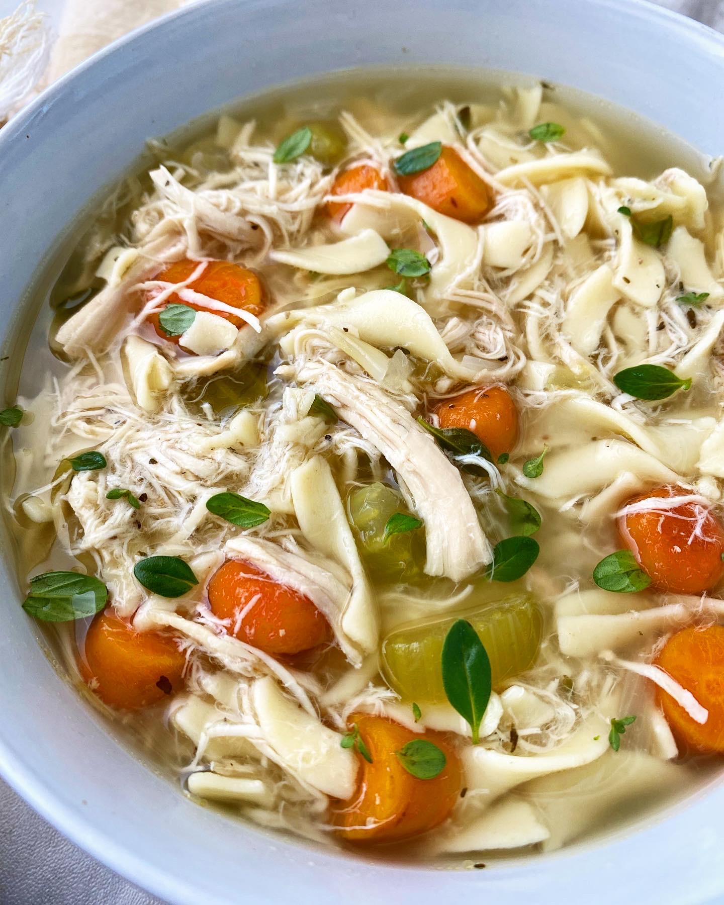 close up, side shot of chicken noodle soup in a white bowl