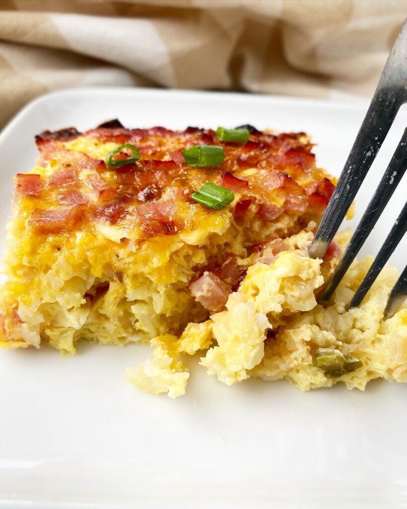 breakfast casserole on a white plate with a fork in it