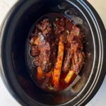 overhead shot of cooked beef back ribs in a black slow cooker