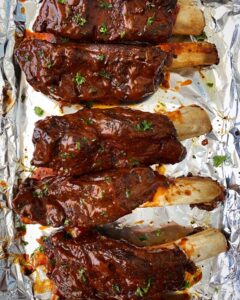 overhead shot of cooked bbq beef ribs on a baking sheet lined with foil