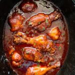 cooked bbq chicken drumsticks in a black crockpot
