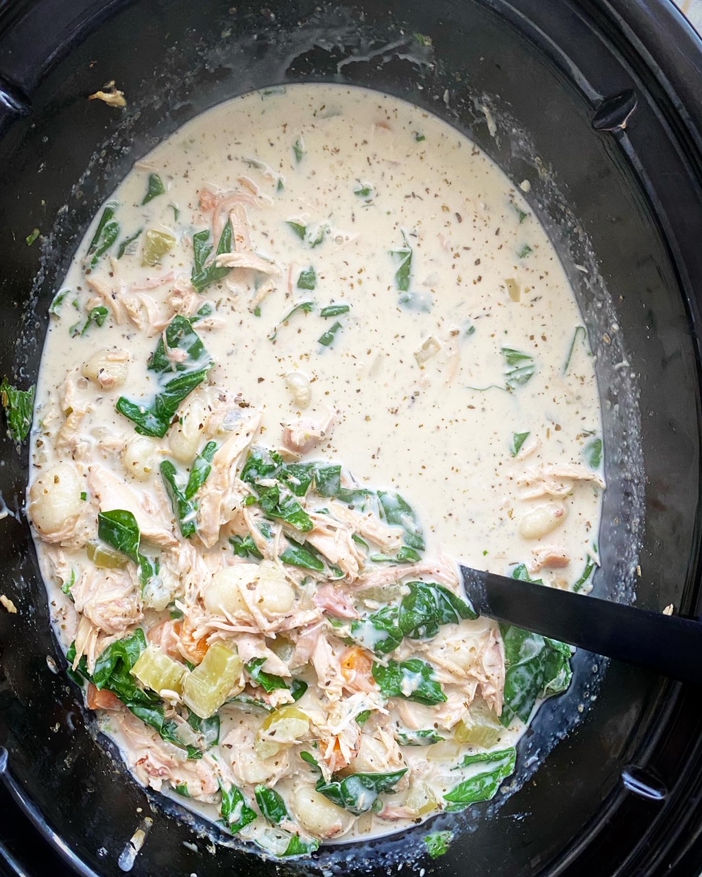 overhead shot of cooked Chicken Gnocchi Soup in a black crockpot