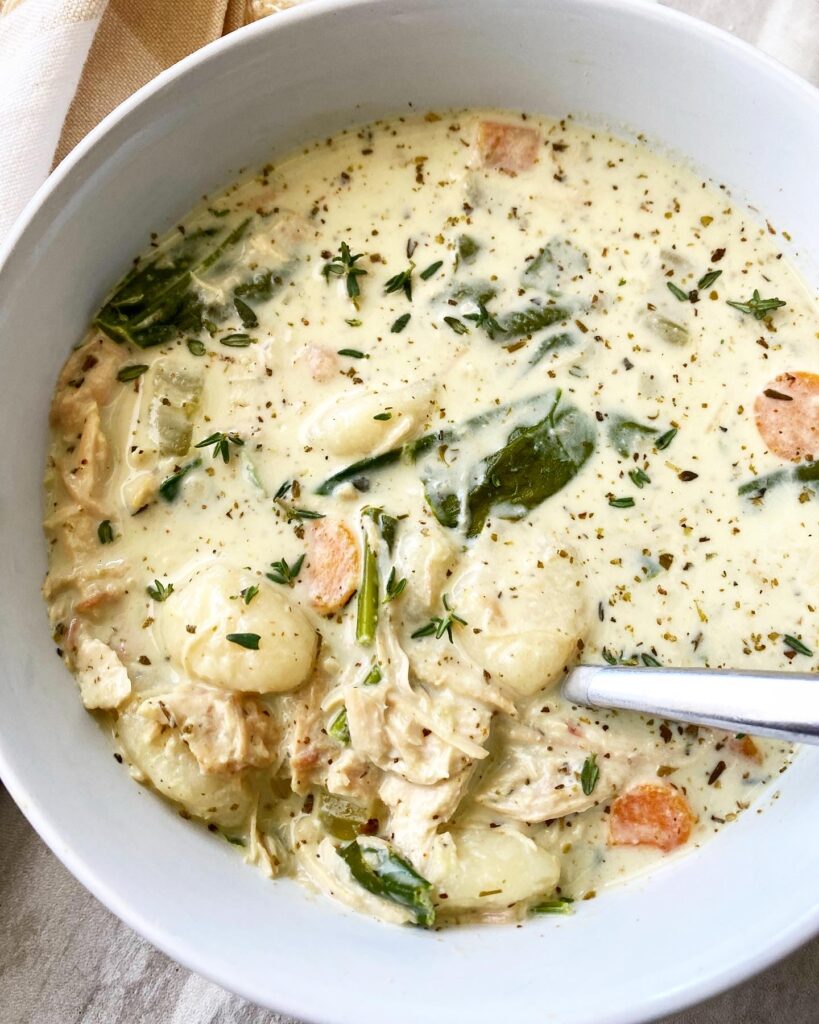 overhead shot of cooked Chicken Gnocchi Soup in a white bowl with a silver spoon in it