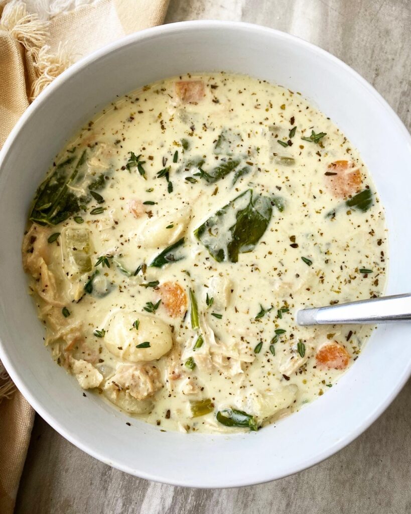 overhead shot of cooked Chicken Gnocchi Soup in a white bowl with a silver spoon in it