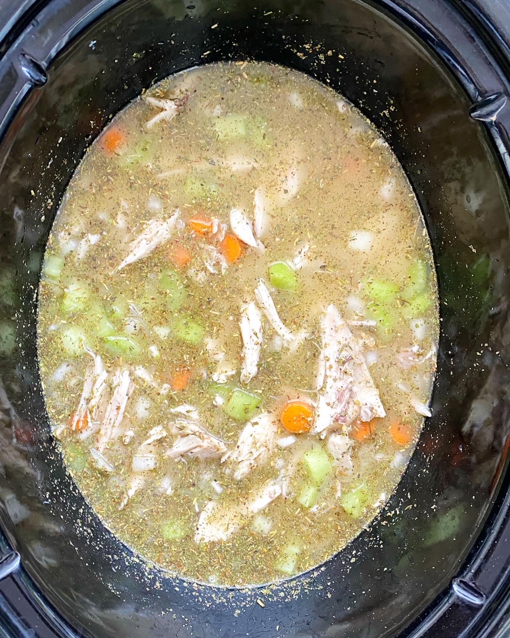 overhead shot of uncooked Chicken Gnocchi Soup in a black crockpot