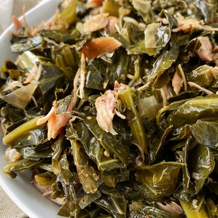 overhead close up shot of cooked greens with smoked turkey in a white bowl