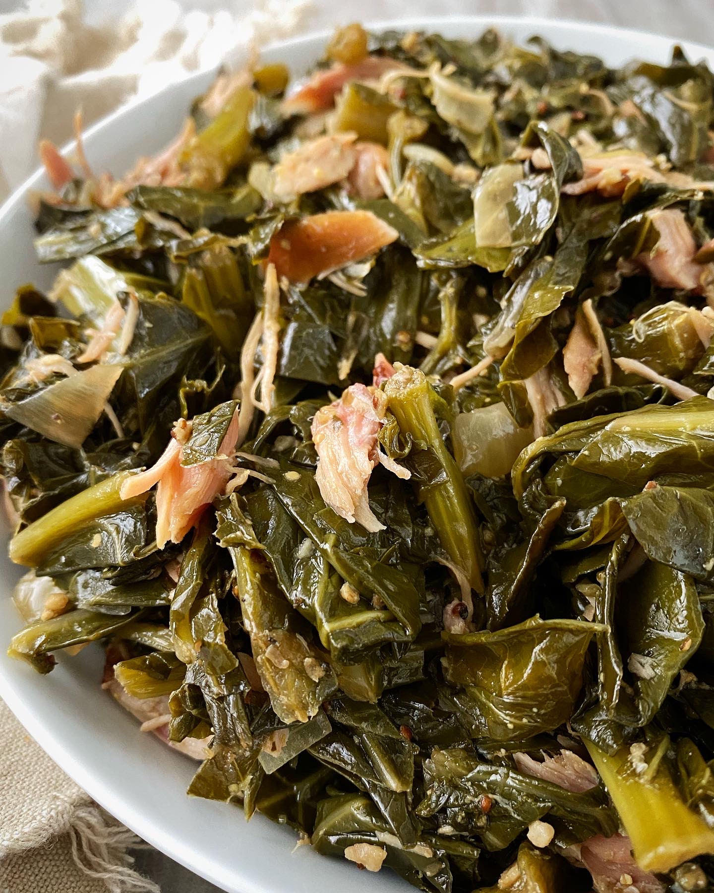 overhead close up shot of cooked greens with smoked turkey in a white bowl