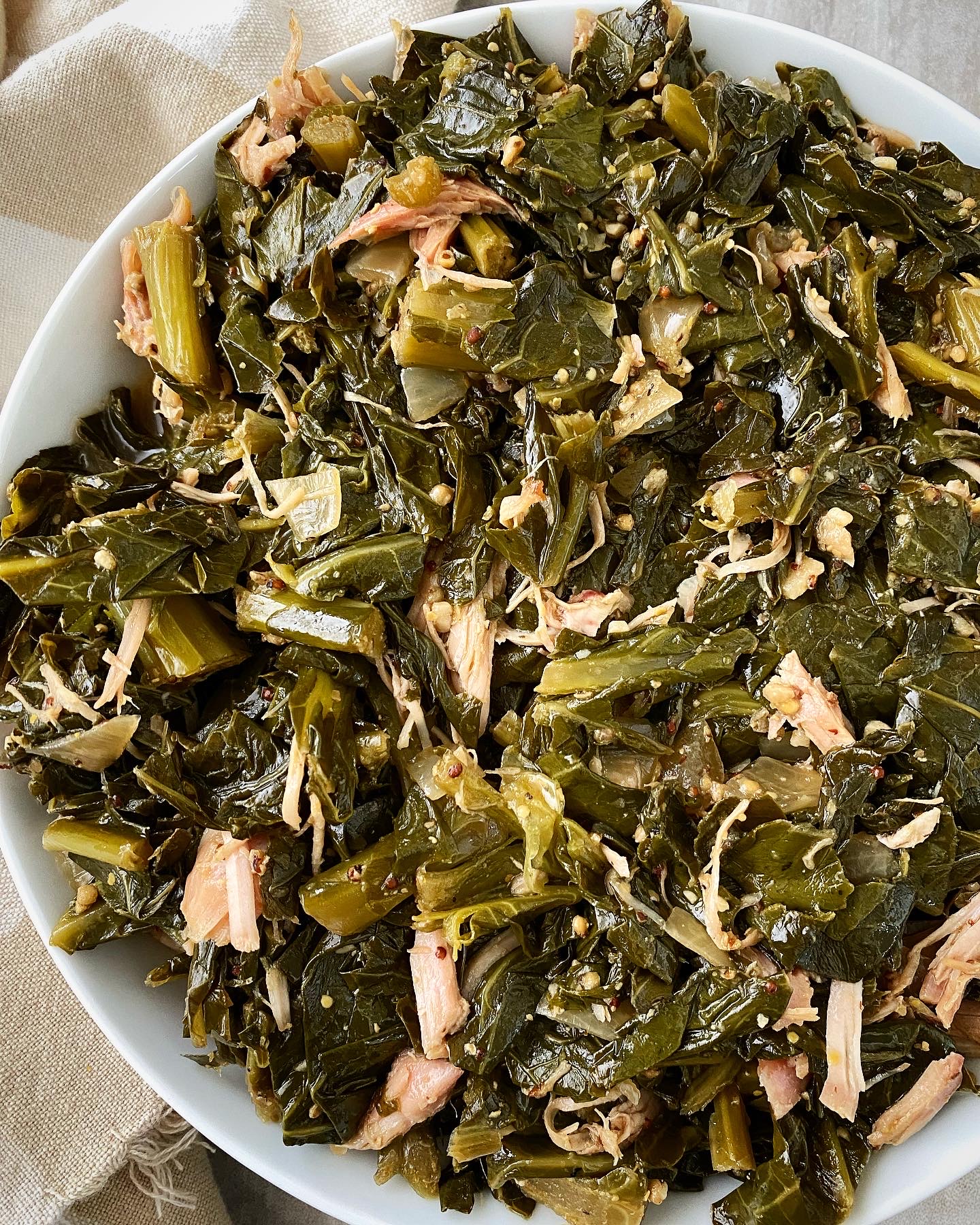 overhead shot of cooked greens with smoked turkey in a white bowl
