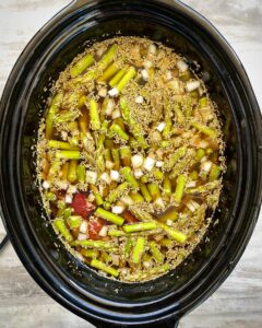 overhead shot of uncooked surf & turf soup in a black slow cooker
