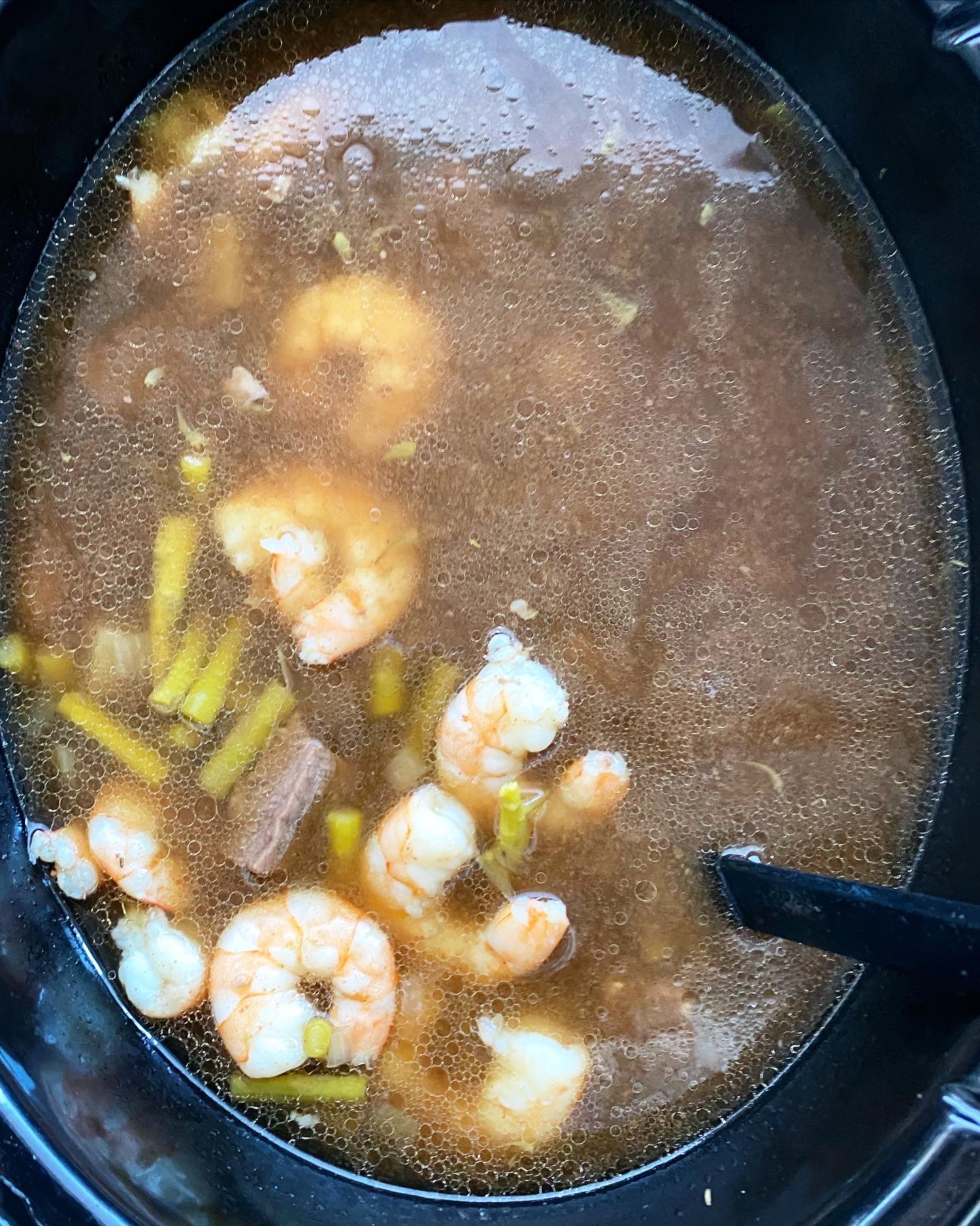 overhead shot of cooked surf & turf soup in a black slow cooker