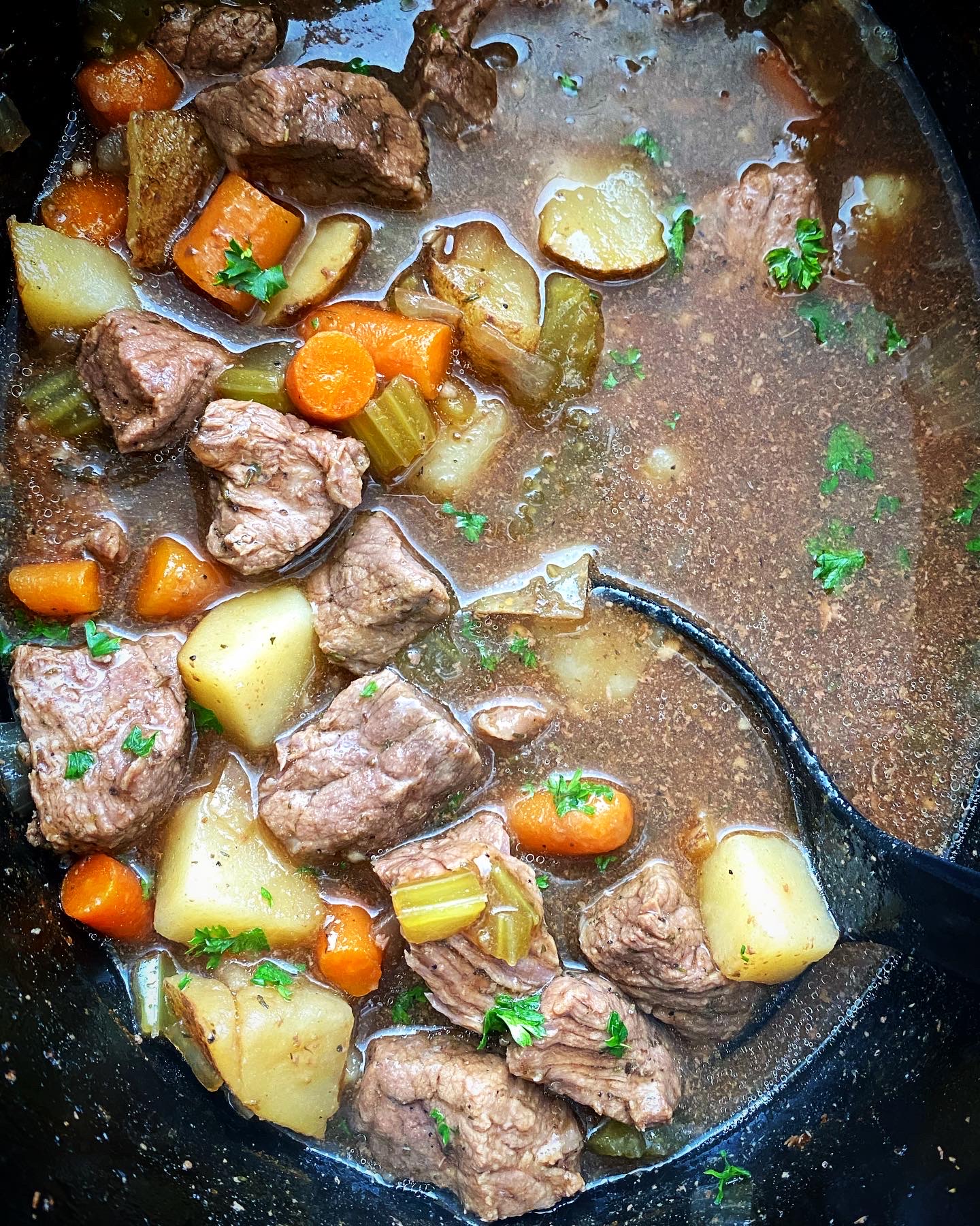 overhead shot of cooked Guinness beef stew in a black slow cooker