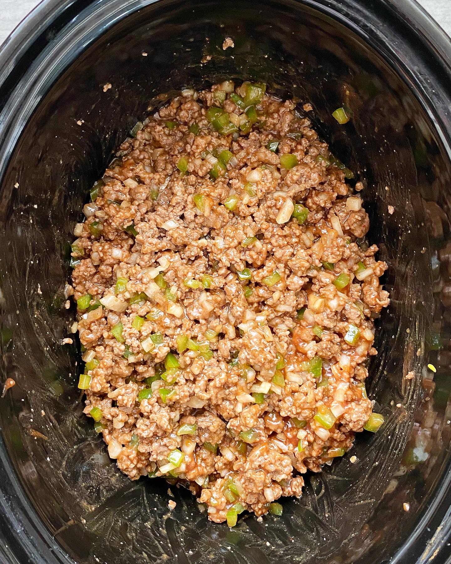 overhead shot of uncooked slow cooker sloppy joes in a black slow cooker