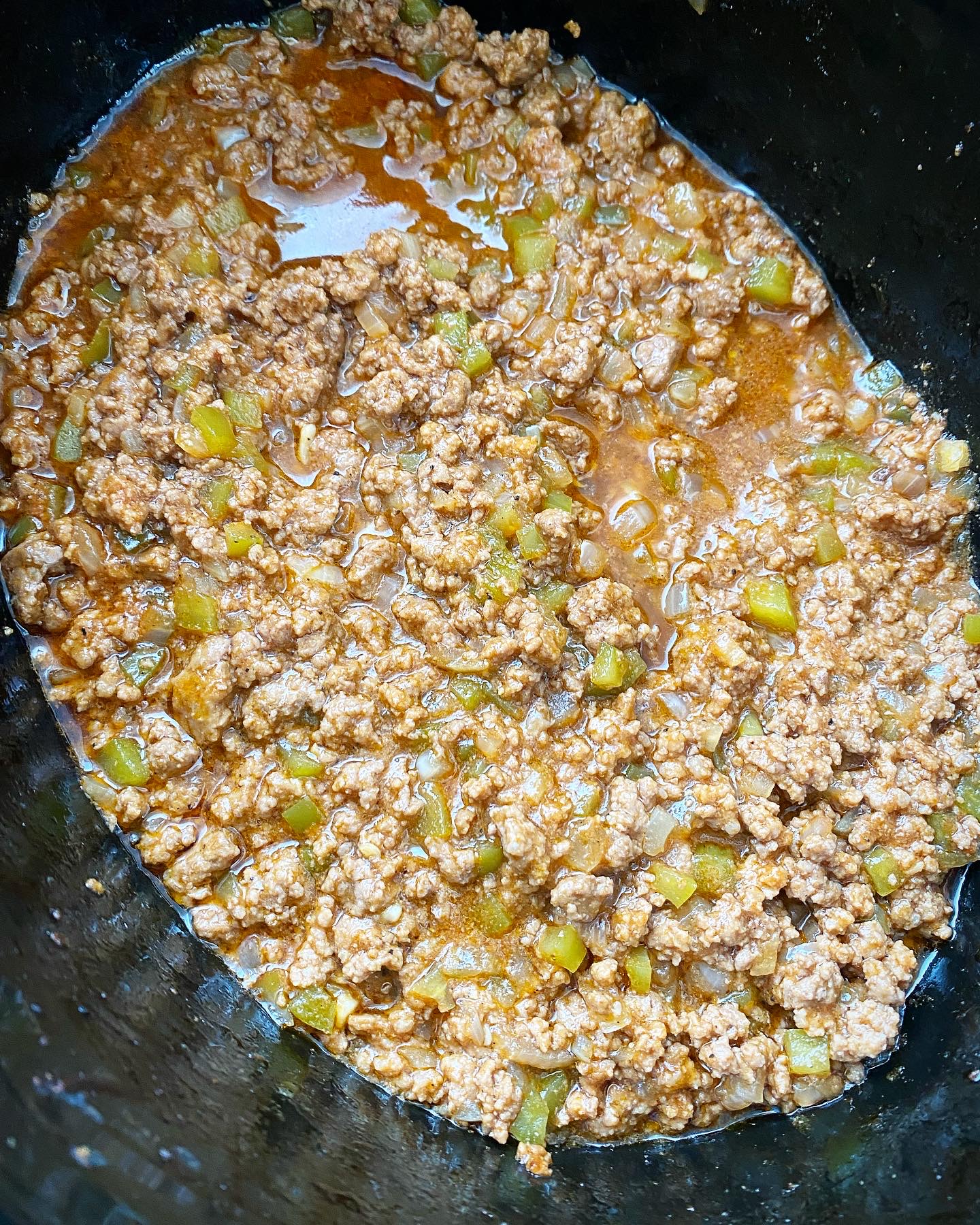 overhead shot of cooked slow cooker sloppy joes in a black slow cooker