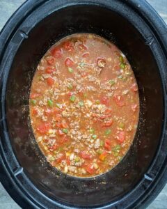 overhead shot of uncooked ground beef spanish rice in a black slow cooker