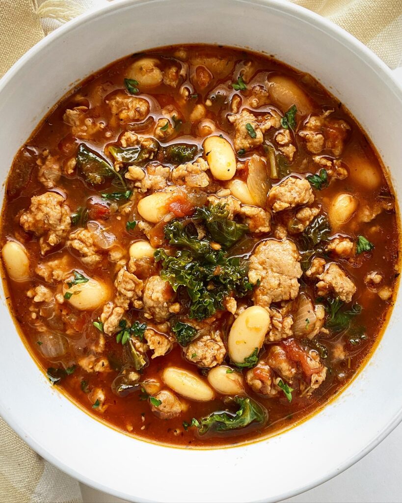overhead shot of cooked sausage white bean soup in a white bowl