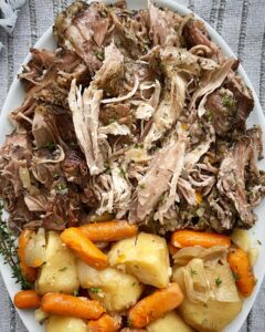 overhead shot of cooked crockpot roast pork on a white plate