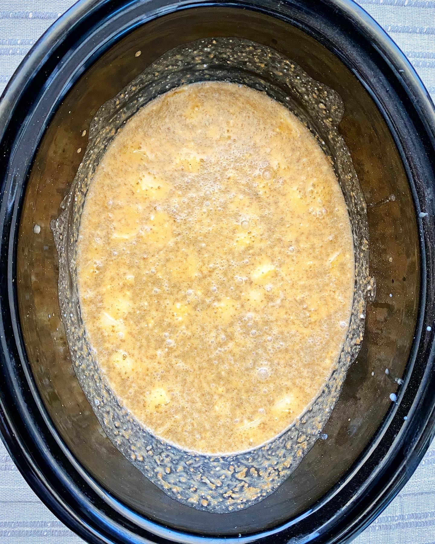 overhead shot of uncooked crockpot pumpkin bisque in a black slow cooker
